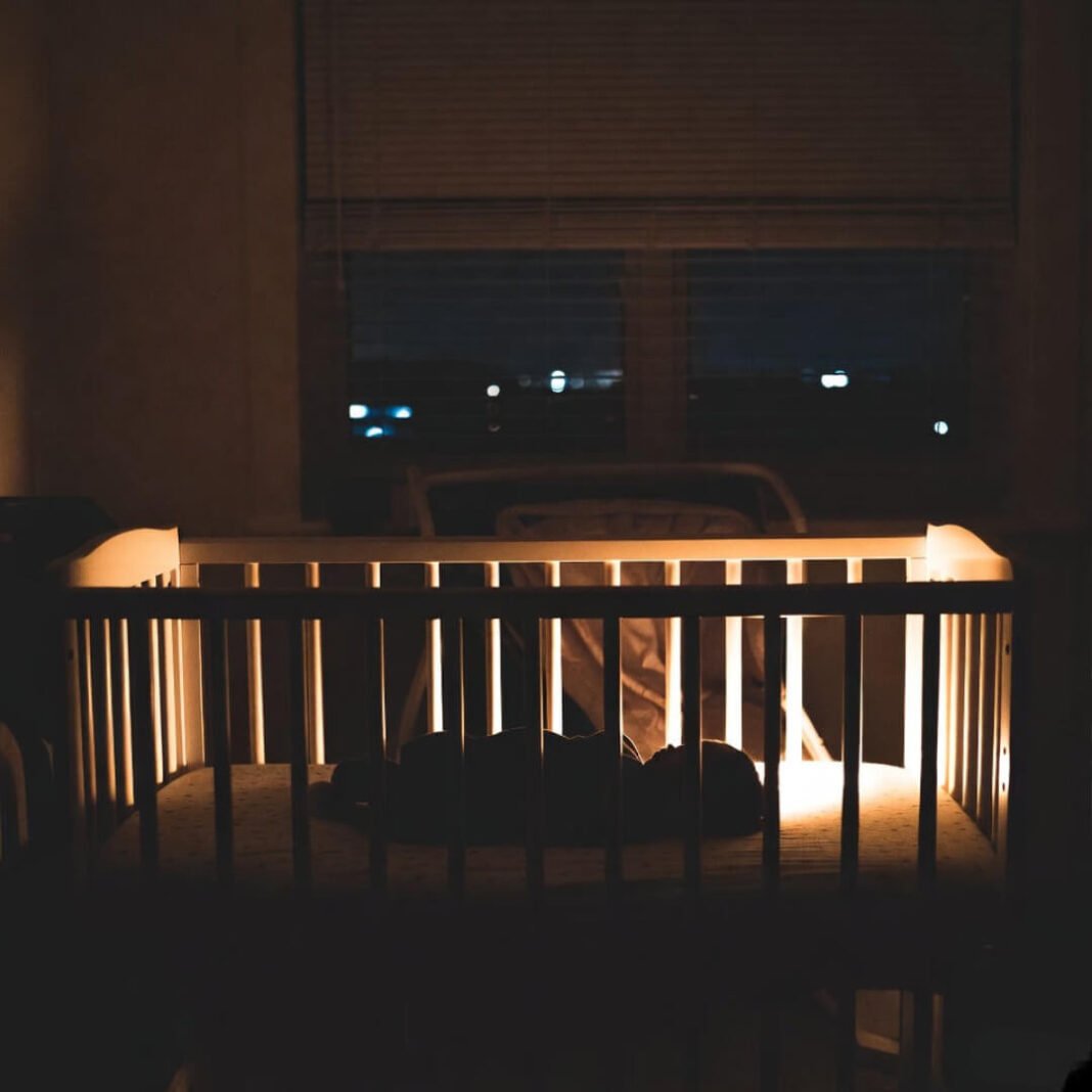 Half-lit crib, city glow at 3 AM.