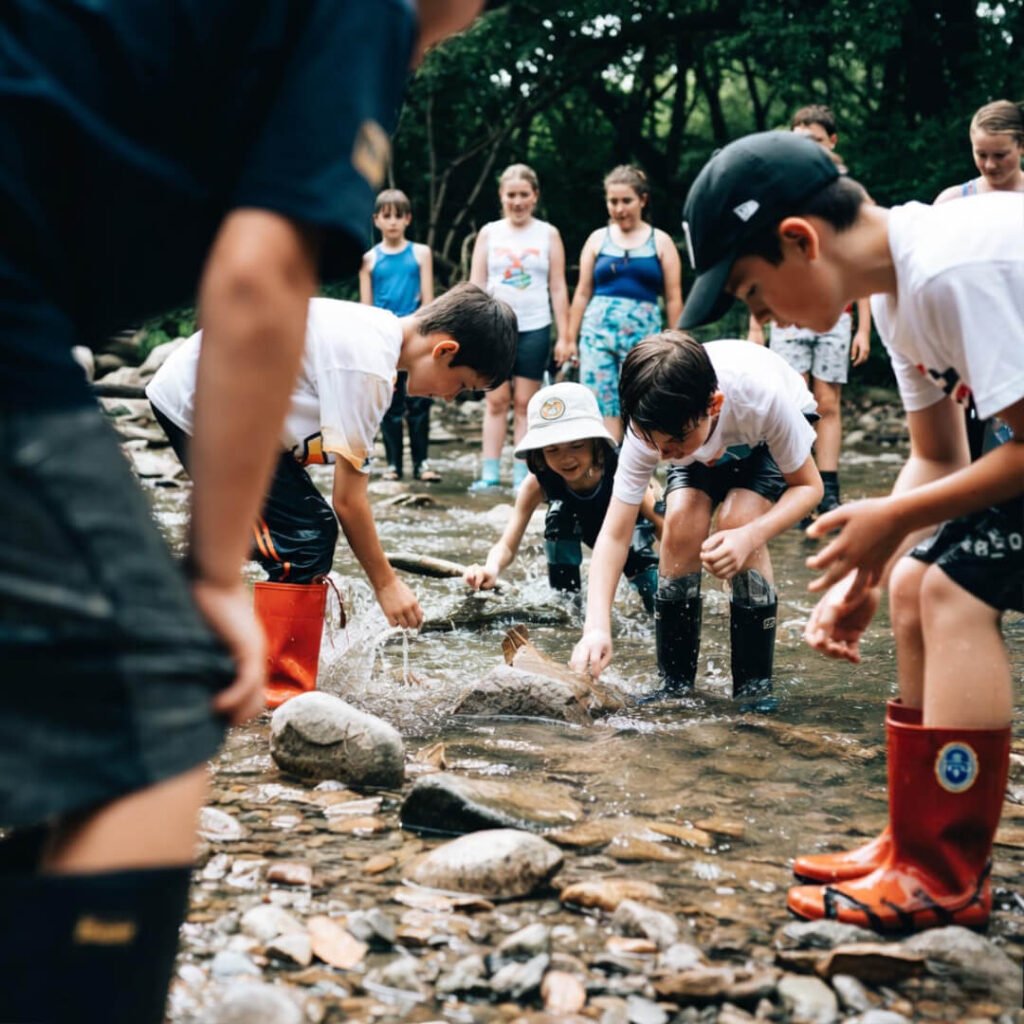 Kids splashing, discovering creek treasures low-angle.