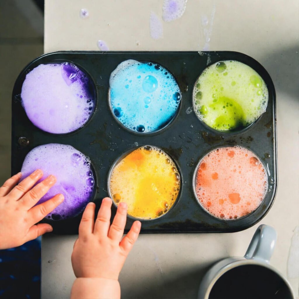 Foaming rainbow potions in muffin tin with toddler hands
